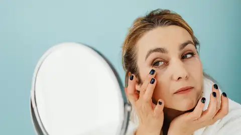Mujer poniéndose crema en las ojeras Mujer poniéndose crema en las ojeras