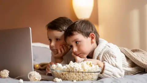 Niños pequeños comiendo palomitas viendo una película Niños pequeños comiendo palomitas viendo una película