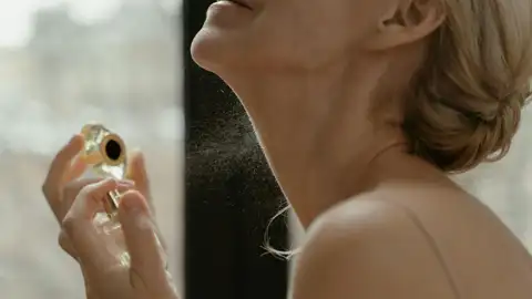 Mujer aplicándose perfume en el cuello Mujer aplicándose perfume en el cuello