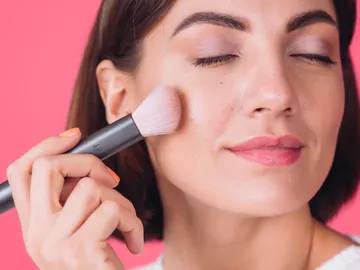 Mujer aplicándose colorete Mujer aplicándose colorete