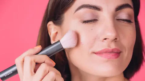 Mujer aplicándose colorete Mujer aplicándose colorete