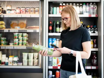 Una mujer analiza con una app la etiqueta de un producto del supermercado Una mujer analiza con una app la etiqueta de un producto del supermercado