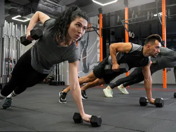 Mujeres y hombres haciendo ejercicios de fuerza en el gimnasio Mujeres y hombres haciendo ejercicios de fuerza en el gimnasio