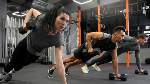 Mujeres y hombres haciendo ejercicios de fuerza en el gimnasio Mujeres y hombres haciendo ejercicios de fuerza en el gimnasio