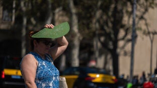 Imagen de archivo de una mujer protegi&eacute;ndose del sol con su abanico. 
