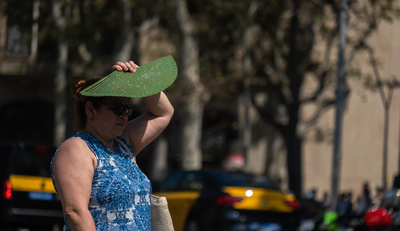 Imagen de archivo de una mujer protegiéndose del sol con su abanico.