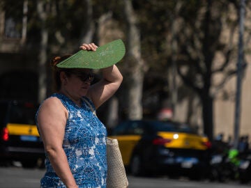 Imagen de archivo de una mujer protegiéndose del sol con su abanico. 