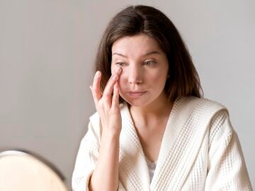 Mujer aplic&aacute;ndose crema en la ojera