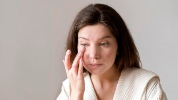 Mujer aplicándose crema en la ojera