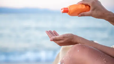 Mujer en la playa con crema solar Mujer en la playa con crema solar