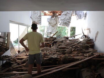Un residente israelí inspecciona su sala de estar dañada tras un ataque con misiles iraníes contra un complejo residencial en Tel Aviv