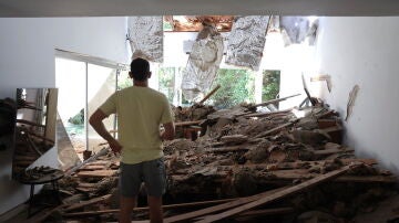 Un residente israelí inspecciona su sala de estar dañada tras un ataque con misiles iraníes contra un complejo residencial en Tel Aviv