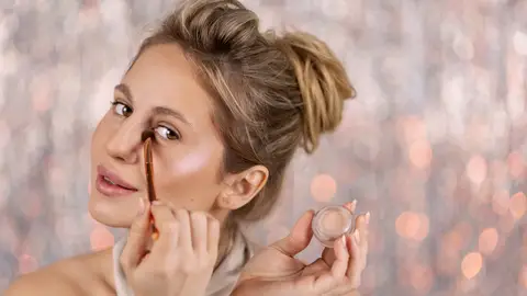 Mujer aplicándose iluminador Mujer aplicándose iluminador