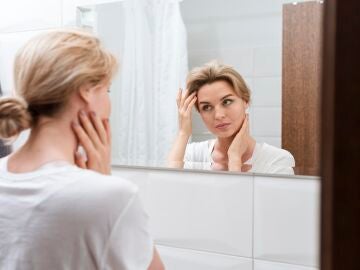 Mujer mir&aacute;ndose el rostro en el espejo