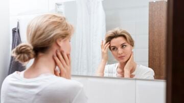 Mujer mirándose el rostro en el espejo