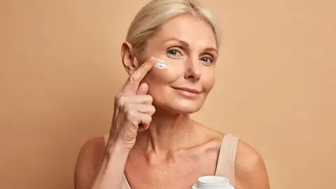 Mujer aplicándose cosmético en la cara Mujer aplicándose cosmético en la cara