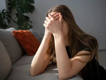 Una mujer tapándose la cara por ansiedad Una mujer tapándose la cara por ansiedad