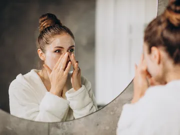 Mujer aplicándose cosmético en la cara Mujer aplicándose cosmético en la cara