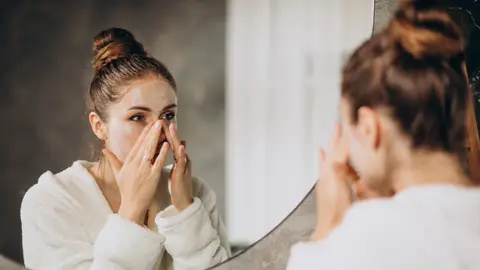 Mujer aplicándose cosmético en la cara Mujer aplicándose cosmético en la cara