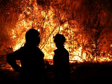 Bomberos forestales antes las grandes llamas del incendio en Aguasmestas, una parroquia del municipio de Quiroga, en la provincia de Lugo