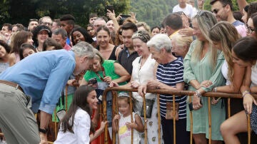 El rey Felipe VI (i) y la reina Letizia (c) saludan a vecinos durante su visita