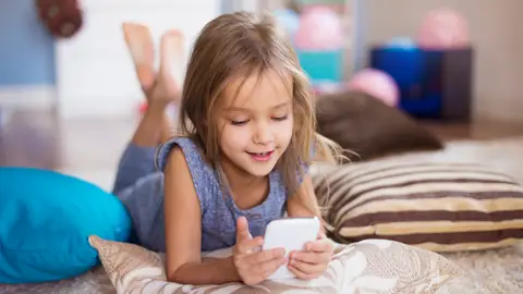 Niña con un móvil en la mano Niña con un móvil en la mano