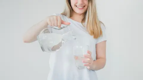 Mujer sirviendo agua de una jarra Mujer sirviendo agua de una jarra