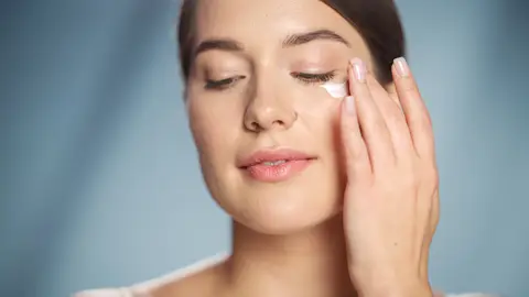 Chica aplicándose contorno de ojos Chica aplicándose contorno de ojos