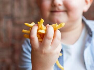 Un niño cogiendo patatas fritas Un niño cogiendo patatas fritas