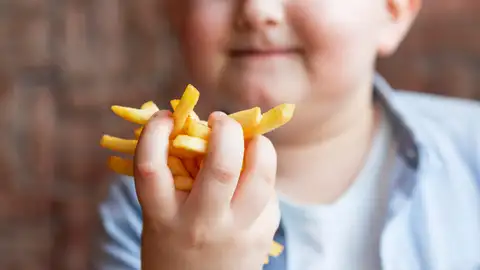 Un niño cogiendo patatas fritas Un niño cogiendo patatas fritas