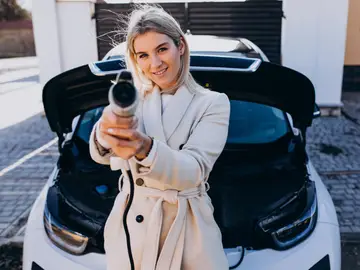 Mujer cargando un coche eléctrico Mujer cargando un coche eléctrico