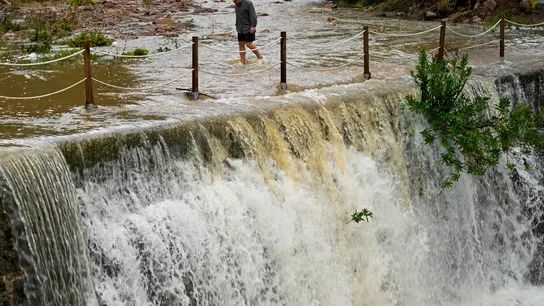 Un hombre cruza un badén inundable Un hombre cruza un badén inundable