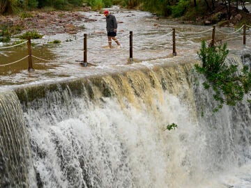 Un hombre cruza un badén inundable