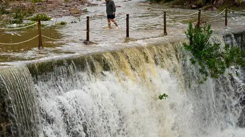 Un hombre cruza un badén inundable Un hombre cruza un badén inundable