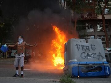 Un contenedor quemado y una persona con la cara tapada en las protestas en favor de Palestina Un contenedor quemado y una persona con la cara tapada en las protestas en favor de Palestina