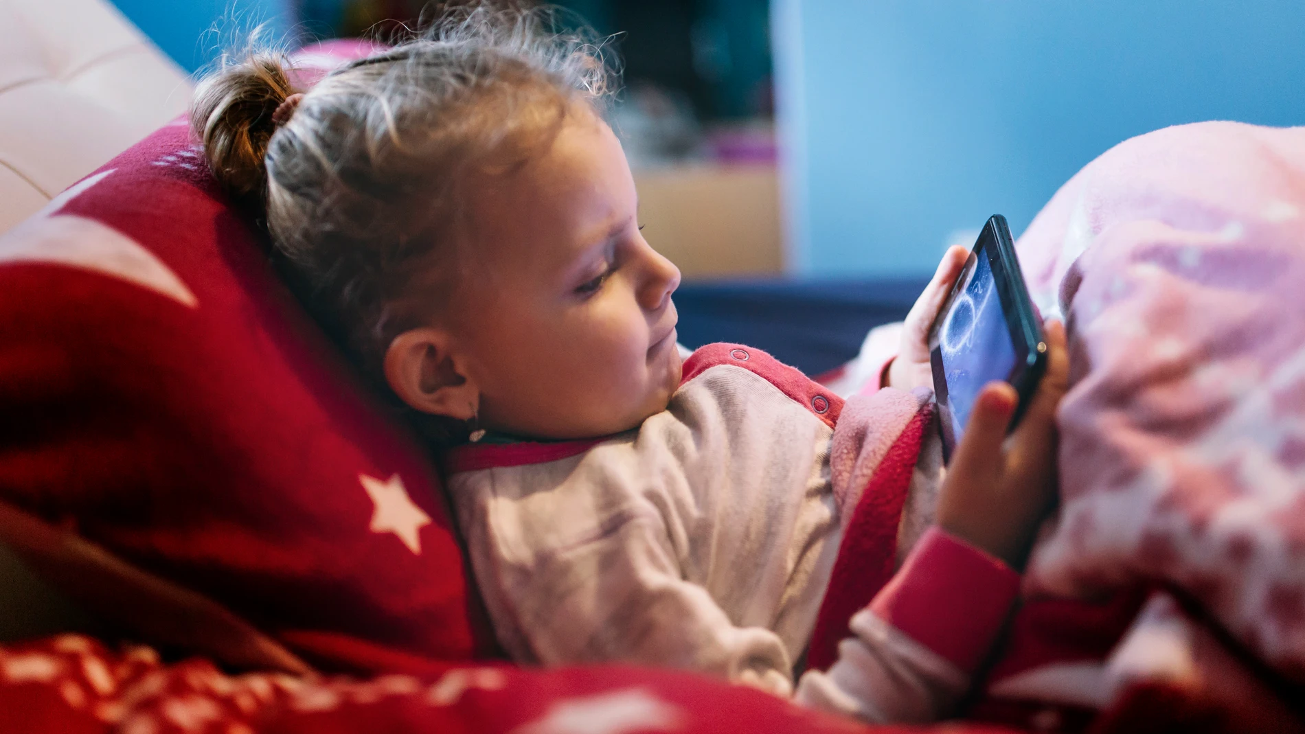 Una niña con el móvil en la cama Una niña con el móvil en la cama