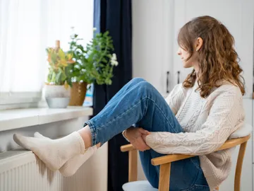 Mujer con los pies en el radiador Mujer con los pies en el radiador