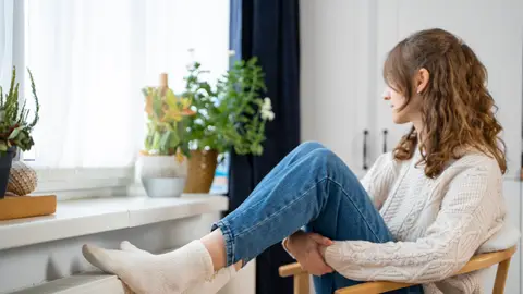 Mujer con los pies en el radiador Mujer con los pies en el radiador