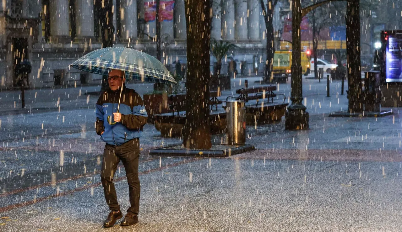 Imagen de un hombre protegiéndose de la granizada caída el viernes en Bilbao