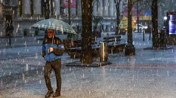 Imagen de un hombre protegiéndose de la granizada caída el viernes en Bilbao Imagen de un hombre protegiéndose de la granizada caída el viernes en Bilbao