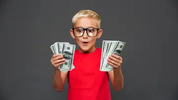Un niño muy contento con dinero en las manos Un niño muy contento con dinero en las manos
