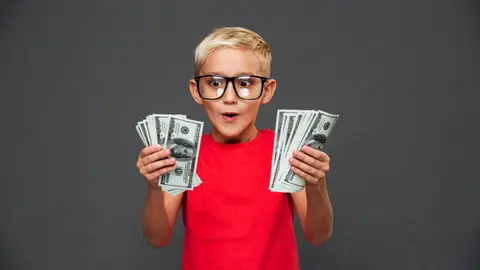 Un niño muy contento con dinero en las manos Un niño muy contento con dinero en las manos