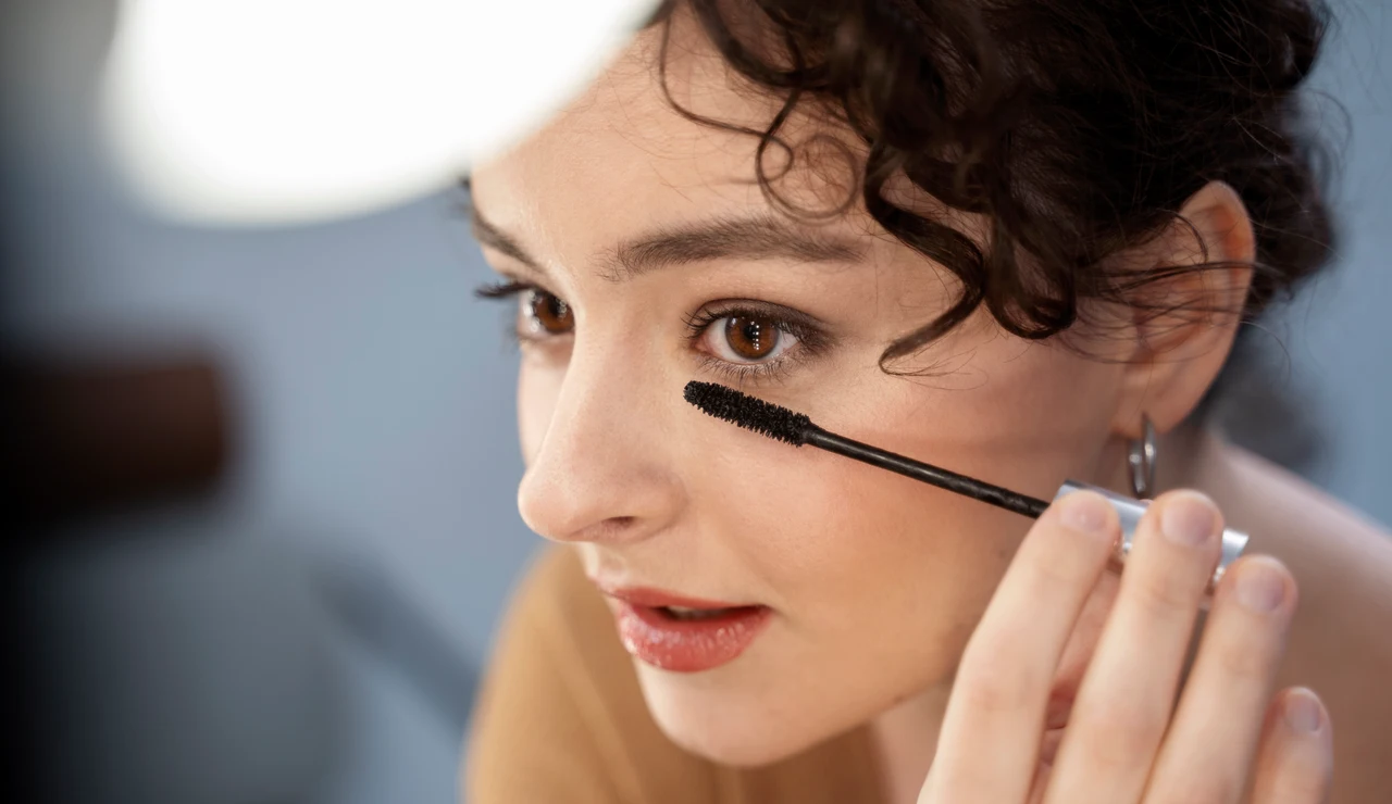 Mujer aplicándose máscaras de pestañas