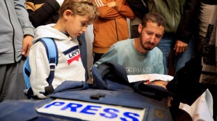 Gazat&iacute;es contemplan el cuerpo un periodista palestino asesinado.