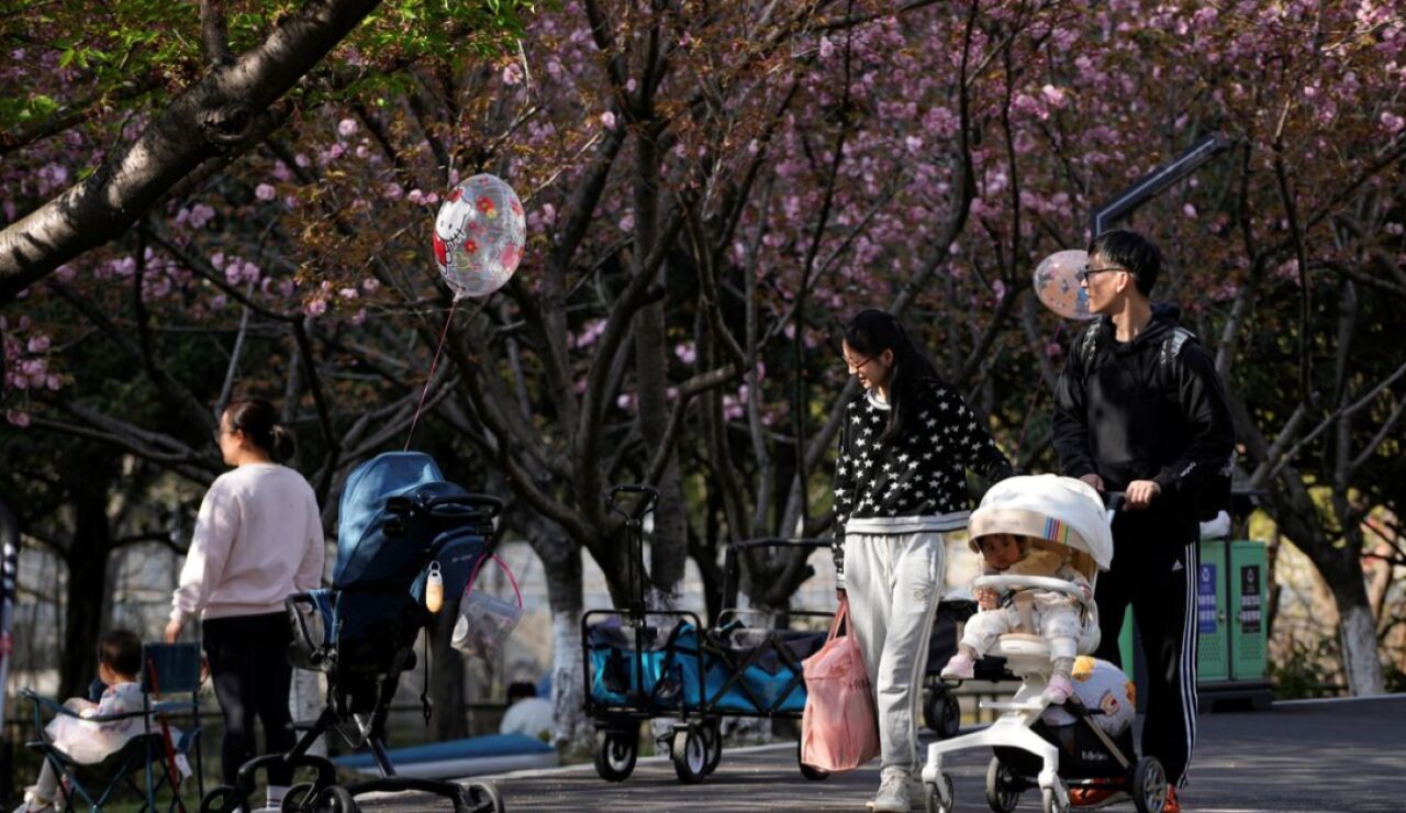 Una pareja pasea con un carrito por un parque en Pek&iacute;n