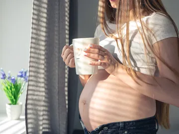 Una embarazada con una taza Una embarazada con una taza