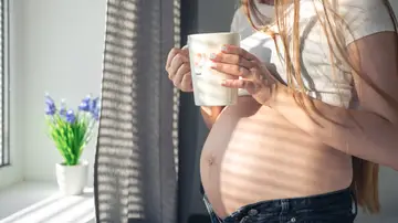 Una embarazada con una taza Una embarazada con una taza