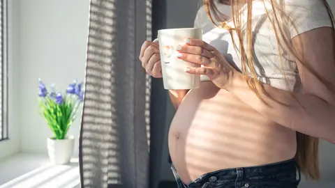 Una embarazada con una taza Una embarazada con una taza