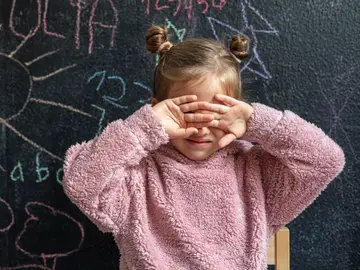 Una niña se tapa la cara con las manos Una niña se tapa la cara con las manos