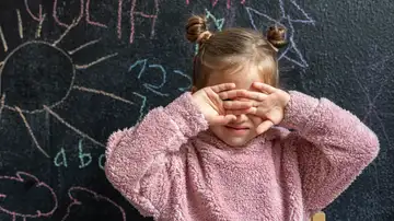 Una niña se tapa la cara con las manos Una niña se tapa la cara con las manos